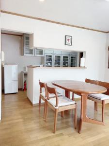 松户市Young House的带木桌和椅子的厨房以及带冰箱的厨房。
