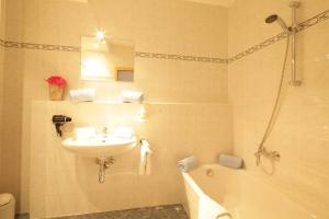 克舍尔阿尔潘公园公寓式酒店的浴室配有盥洗盆、卫生间、浴缸和盥洗盆。