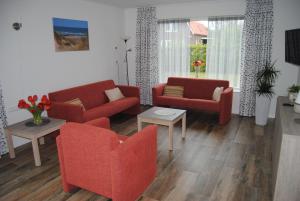东卡佩勒Villa Dunopark 49的客厅配有两张红色的沙发和一张桌子