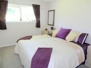 卡林顿Beautiful 3-Bed Cottage in Cornwall的卧室配有一张带紫色枕头的大型白色床。