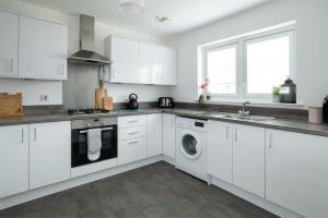 因弗内斯Lily Bank House的厨房配有白色橱柜、洗衣机和烘干机