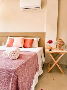 嘎林海斯港Pousada Praiana的一间卧室配有一张带红色枕头的床和一张桌子
