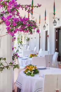 克罗托内Hotel Lido degli Scogli的一间设有白色桌子和紫色鲜花的用餐室