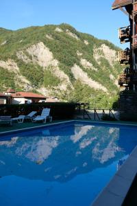 蒙泰克雷托GranChalet sul Cimone I love Montecreto 103的一个带椅子的游泳池,后方是一座山。