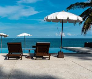 拉迈The Hive Hotel的海滩上的两把椅子和一张桌子及一把遮阳伞