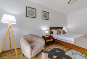 布什泰尼Yael Luxury Apartments 4的一间卧室配有一张床、一把椅子和一盏灯