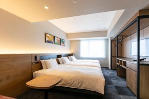 大阪Hotel Forza Osaka Namba的一间卧室配有两张床和一张桌子