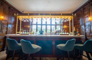 埃文河畔斯特拉特福比尔斯利庄园酒店的一间酒吧,配有蓝色的椅子和窗户