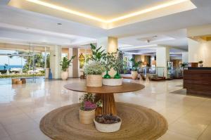阿尔布费拉法雷西亚波尔图湾酒店的大堂设有桌子,上面有盆栽植物