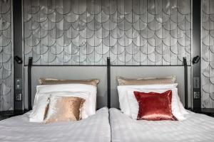奥卢原始艾瑞娜斯科酒店的一间卧室配有带白色床单和红色枕头的床。
