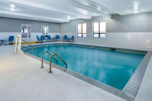 罗切斯特Baymont by Wyndham Rochester Mayo Clinic Area的大楼内带蓝色椅子的游泳池