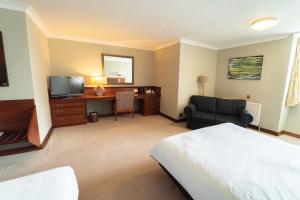 比斯特Littlebury Hotel的酒店客房配有一张床、一张书桌和一台电视。