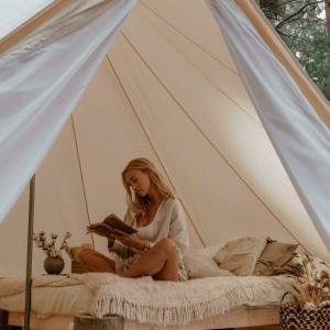 ZunaPop-up glamping - Buurvrouws' Belltentje 2-4 pers的坐在床上读书的女人