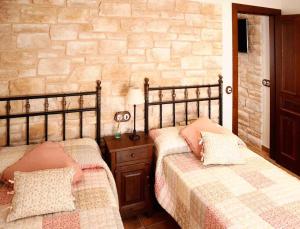 卢安科Casa Rural La Tayuela的一间卧室设有两张床和石墙