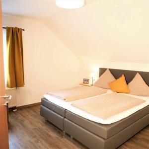 朗根阿根Haus Apfelblüte的一间卧室配有一张带橙色枕头的大床