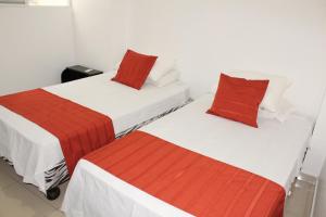 曼塔Departamentos de 2 y 3 Habitaciones en el Centro de MANTA的白色客房的两张床,配有红色枕头