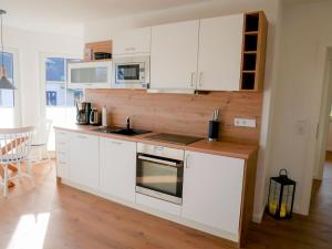 奥特里德维茨Reethaus Boddenblick - Apt. 09的厨房配有白色橱柜和炉灶烤箱。