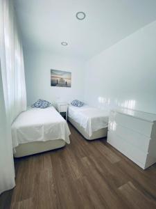 阿尔姆尼卡PRECIOSO APARTAMENTO EN EL TESORILLO的配有白色墙壁和木地板的客房内的两张床