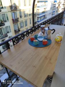尼斯Pretty and quiet top floor 2 bedroom flat in the port area of Nice的阳台上配有带杯子和茶壶的木桌