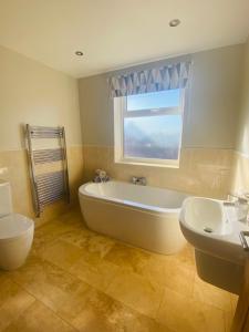 斯卡伯勒Acacia Breezes - Delightful Scarborough Semi的带浴缸、水槽和窗户的浴室