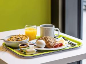 普拉特恩巴塞尔普拉特恩宜必思快捷酒店的托盘,包括早餐食品和一杯橙汁