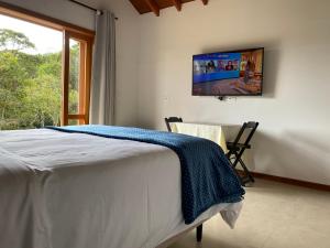 圣安东尼奥-杜皮尼亚尔Villaggio da Mata的卧室配有一张床铺,墙上配有电视