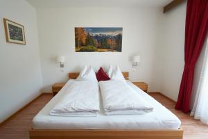 圣马蒂诺Privatpension Bergkristall的一间卧室配有带白色床单和红色枕头的床。