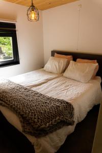 罗斯马伦Het creijennest Gemeente 's-Hertogenbosch的一间卧室配有一张带白色床单的床和一扇窗户。