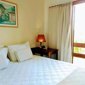 普拉杜古阿比巴宾馆的卧室配有白色的床和带台灯的书桌