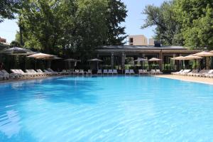 塔什干Radisson Blu Hotel, Tashkent的一个带椅子和遮阳伞的大型游泳池