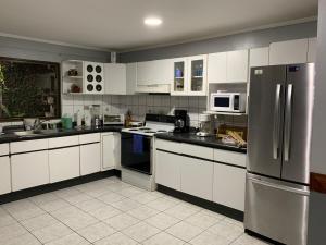阿拉胡埃拉Sunrise by A-1的厨房配有白色橱柜和不锈钢冰箱