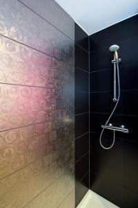 那慕尔里安乡村度假别墅酒店的浴室铺有黑色瓷砖,设有淋浴。
