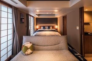 京都Homm Stay Nagi Arashiyama Kyoto By Banyan Group的一间卧室配有一张床和一个沙发