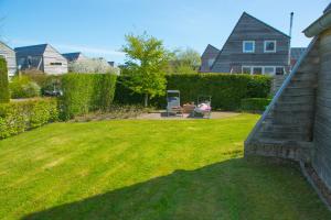 赫劳Fries Vakantiehuis, grote tuin, nabij het Pikmeer的后院,带草坪和房子