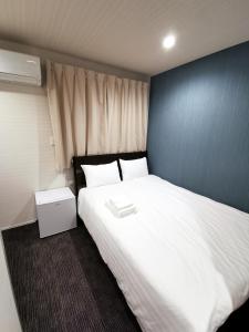 东京东新宿閣楼酒店的卧室配有一张白色大床和蓝色的墙壁