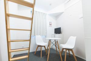 东京东新宿閣楼酒店的一间设有两把椅子、一张桌子和一台电视的房间