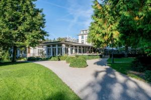 温特图尔Park Hotel Winterthur的一座白色的大建筑,有草坪和树木