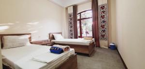 NurotaGuest House Ruslan Nurata & Tours的小房间设有两张床和窗户