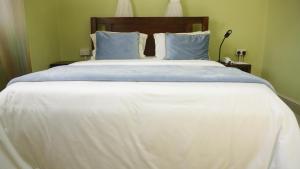 TororoMAMIKKI Hotel Apartments的一张配有白色床单和蓝色枕头的大床