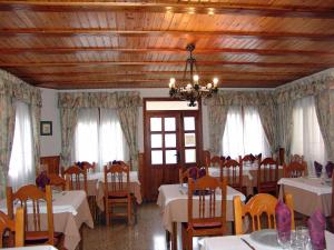 萨尔维塞Hostal Pirineos Sarvisé的餐厅配有白色的桌椅和吊灯