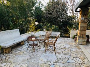 卡萨拉诺Casa famigliare salentina "Mon Rêve" villa del salento的庭院配有两把椅子、一张桌子和一张长凳