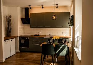 库尔迪加MOOD Apartamenti Kuldīgā的厨房配有绿色橱柜和桌椅