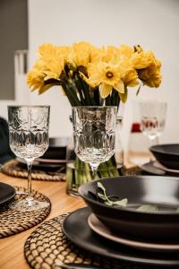 库尔迪加MOOD Apartamenti Kuldīgā的一张桌子,上面有眼镜和一朵黄色花瓶