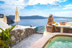 伊亚圣托里尼岛天堂宅酒店的坐在游泳池旁桌子上的女人