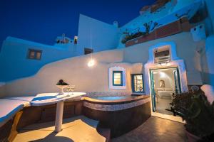 伊亚圣托里尼岛天堂宅酒店的一座带按摩浴缸的建筑,在晚上于庭院里