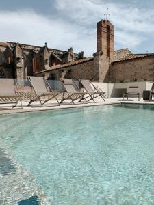 卡斯特罗·德波利亚斯Hotel Palau Macelli的一座带椅子的游泳池以及一座建筑