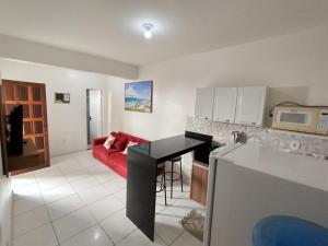 卡波布里奥Cantinho aconchegante 2 quartos, com ar condicionado的厨房以及带红色沙发的起居室。