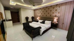 拉希迈尔汗Golden Sand Hotel Rahim Yar Khan的一间卧室配有一张大床和一张黑椅