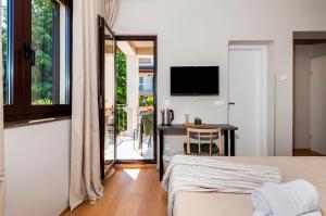罗维尼Sunset Residence Rovinj的一间卧室配有一张床、一张书桌和一台电视