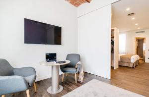 赫罗纳半岛酒店的一间设有桌椅和墙上电视的客房
